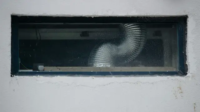 A flexible ventilation duct visible through a small rectangular window.